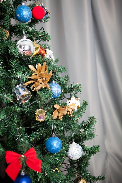 Primo piano sull'albero di natale con ghirlande e decorazioni in casa. Albero verde decorativo e festoso