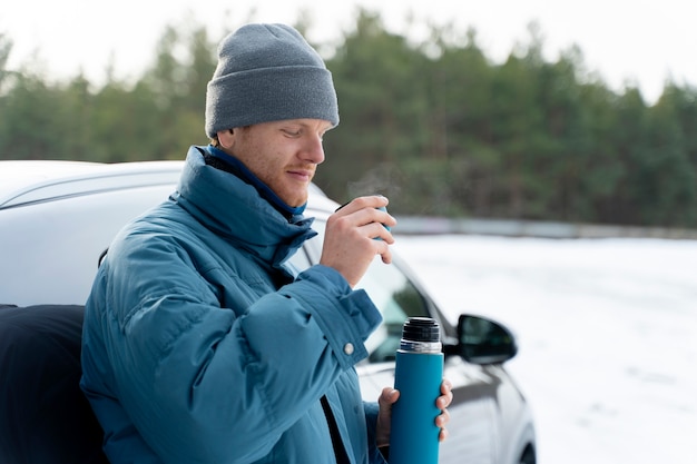 Primo piano sull'uomo che si gode una bevanda calda durante il viaggio invernale