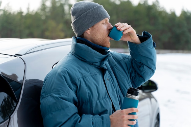 Primo piano sull'uomo che si gode una bevanda calda durante il viaggio invernale