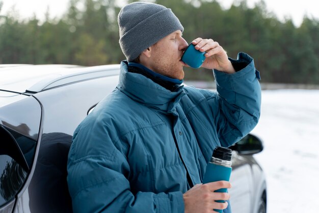 Primo piano sull'uomo che si gode una bevanda calda durante il viaggio invernale