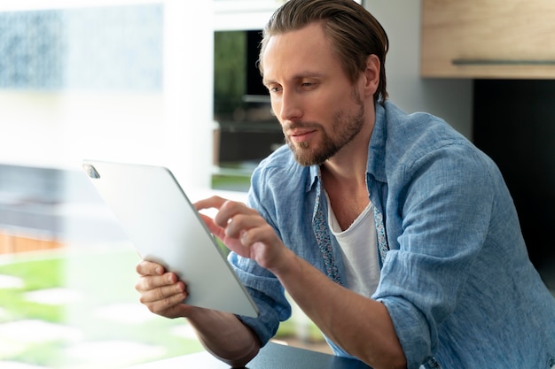 Primo piano sull'uomo che utilizza un dispositivo digitale a casa