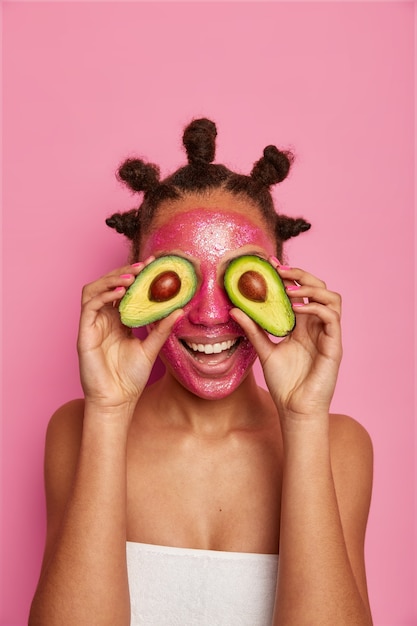 Primo piano sulla donna etnica felice gode di applicare la maschera per il viso isolata