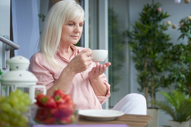 Primo piano sulla donna matura gustando un buon caffè sul balcone