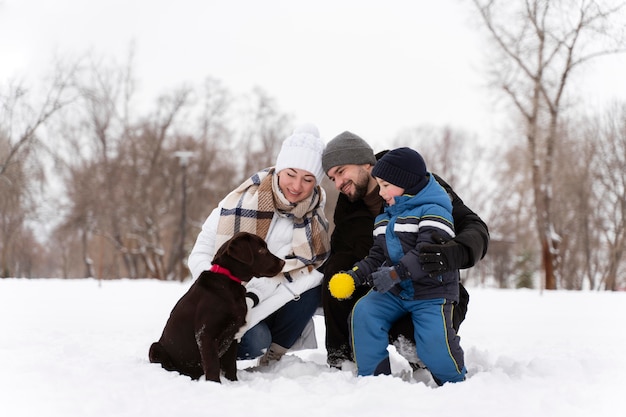 Primo piano sulla famiglia felice che gioca nella neve con il cane