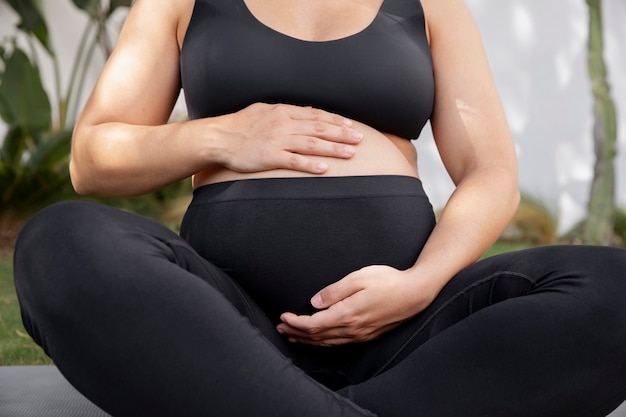 Primo piano sulla giovane donna incinta che fa yoga
