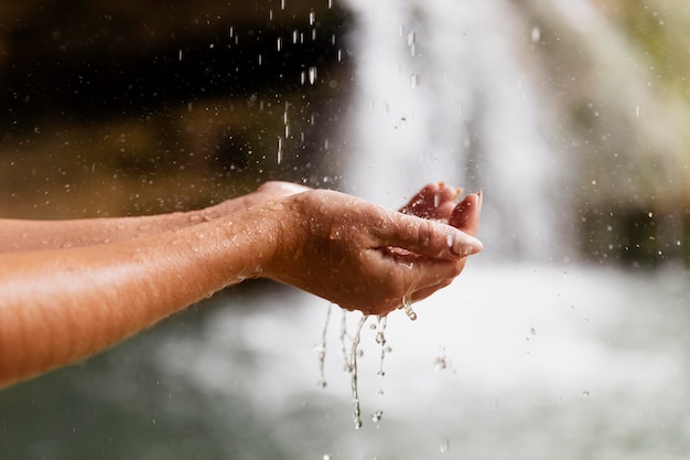 Primo piano sulle mani di un giovane adulto vicino alla cascata