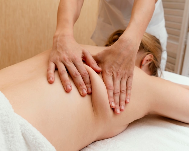 Primo piano terapista che massaggia la schiena della donna