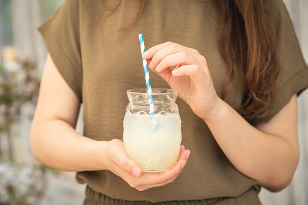 Primo piano un bicchiere di limonata in mani femminili