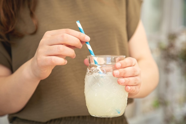 Primo piano un bicchiere di limonata in mani femminili