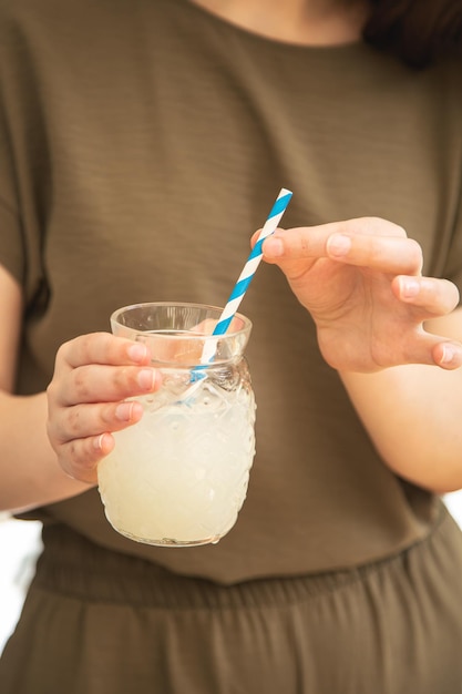 Primo piano un bicchiere di limonata in mani femminili