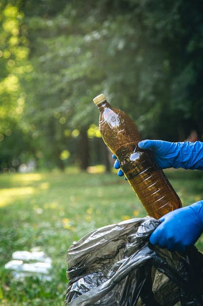 Primo piano una bottiglia di plastica in una mano maschile che pulisce la natura