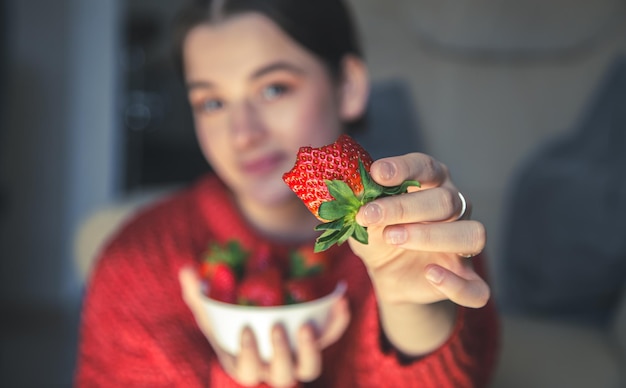 Primo piano una grande fragola appetitosa nelle mani di una giovane donna