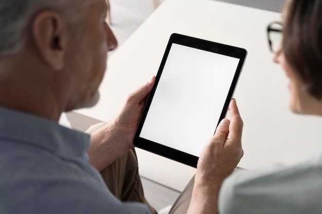 Primo piano uomo anziano che tiene tablet