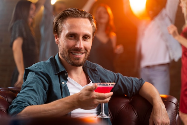 Primo piano uomo che tiene in mano un drink