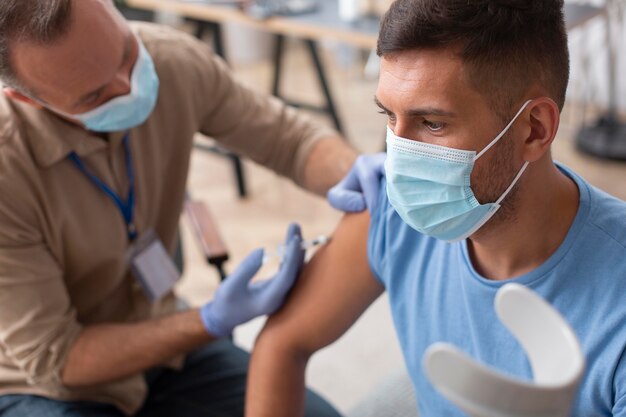 Primo piano uomo con maschera che si fa vaccinare