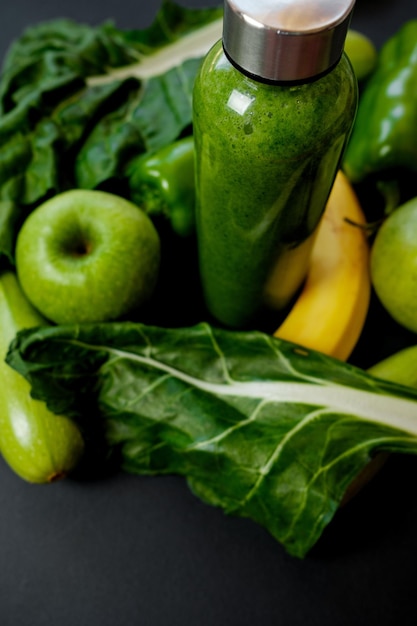 Primo piano Verdure verdi e frullati in una bottiglia di plastica su sfondo nero Concetto sano