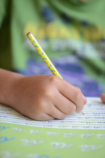 Primo piano verticale di un bambino che impara a scrivere lettere