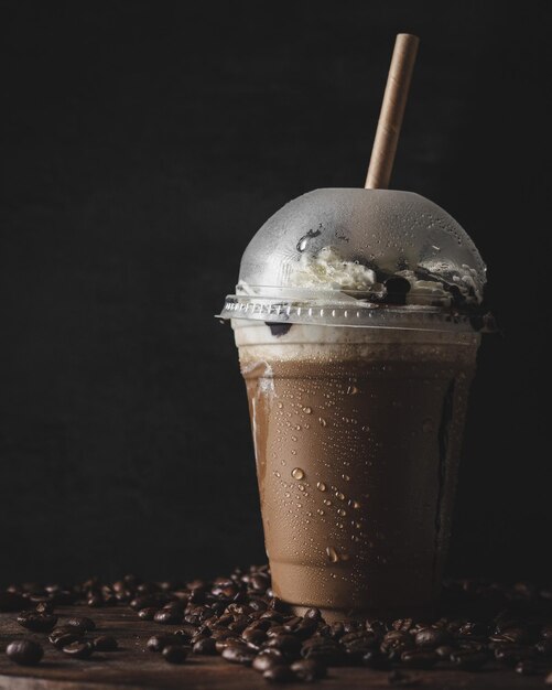 Primo piano verticale di una tazza di plastica di caffè freddo con una crema alla vaniglia