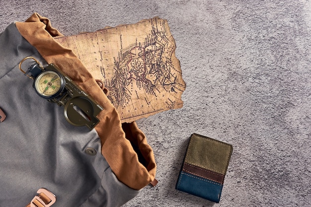 Primo piano vista dall'alto di una bussola posta su un tessuto colorato accanto a un'antica mappa e un portafoglio