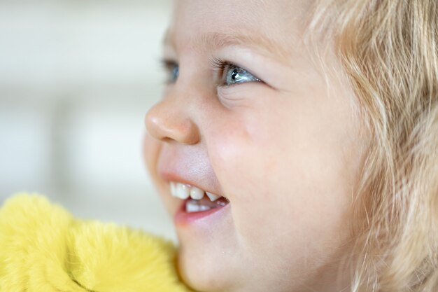 Primo piano volto di una bambina carina con grandi occhi azzurri, ragazza sorridente.