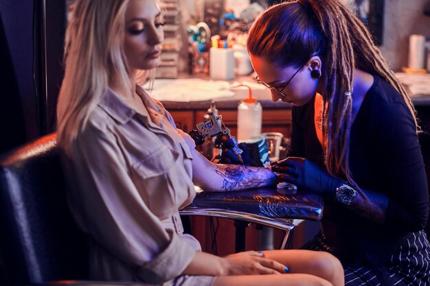 Processo di creazione di un nuovo tatuaggio per la giovane donna da parte di un tatuatore esperto in studio.