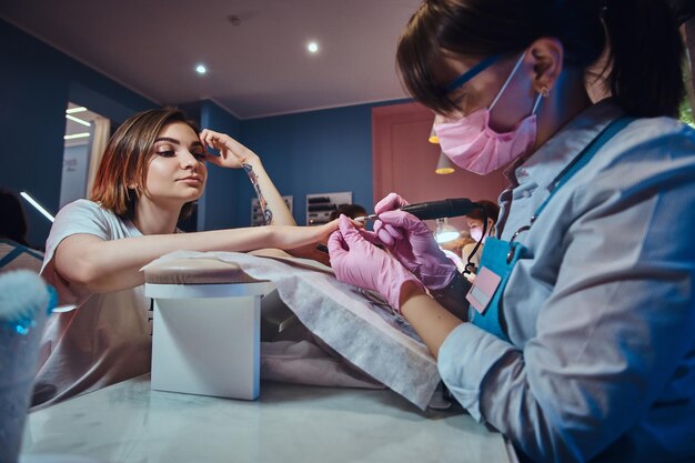 Processo di manicure al salone di bellezza con due donne felici attraenti.