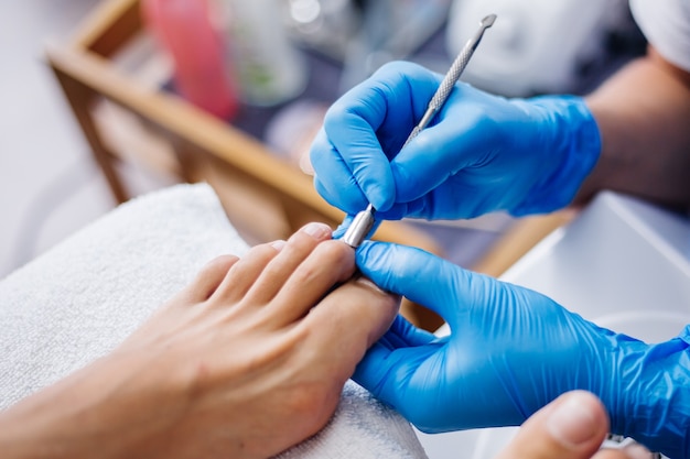 Processo di pedicure Pedicure da salone domestico Trattamento per la cura dei piedi e unghie Il processo di pedicure professionale Il maestro in guanti blu fa la pedicure