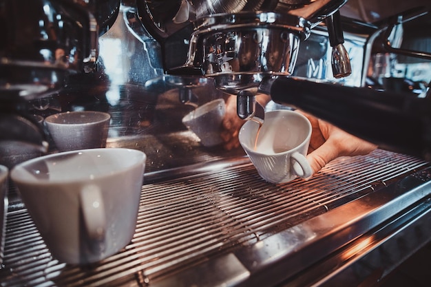 Processo di preparazione del caffè utilizzando la macchina da caffè al ristorante da parte di un barista di talento.