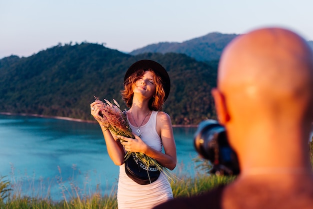 Processo di ripresa video L'uomo prende un video su una fotocamera professionale di giovane donna alla moda blogger in vacanza vista tropicale