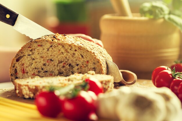 Processo di taglio del pane integrale in cucina. Sfondo della cucina. Processo di cottura. Tonica.