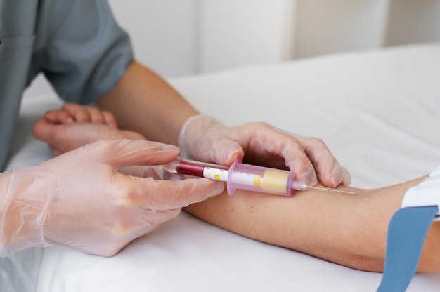 Professionista sanitario di vista laterale che preleva sangue