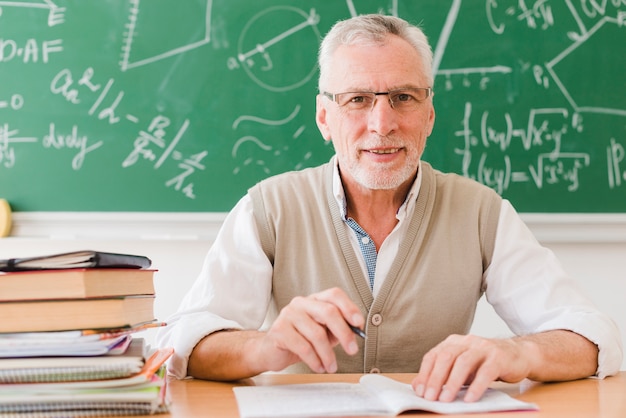 Professore senior che si siede allo scrittorio nella stanza di conferenza