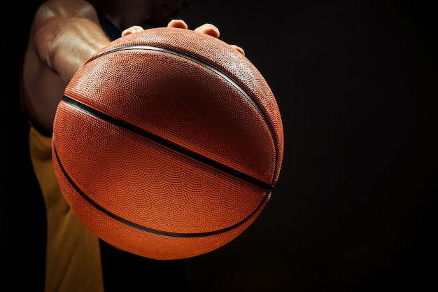 Profili il punto di vista di una palla del canestro della tenuta del giocatore di pallacanestro su fondo nero