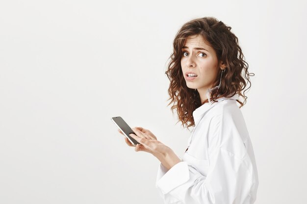 Profilo di donna preoccupata e interessata utilizzando il telefono cellulare