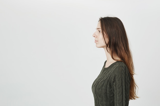 Profilo di giovane donna attraente in maglione verde con capelli lunghi