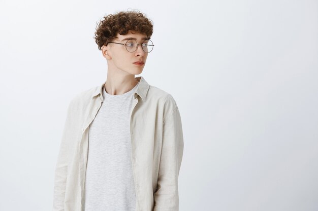 Profilo di giovane ragazzo dai capelli ricci attraente ed elegante con gli occhiali guardando a destra
