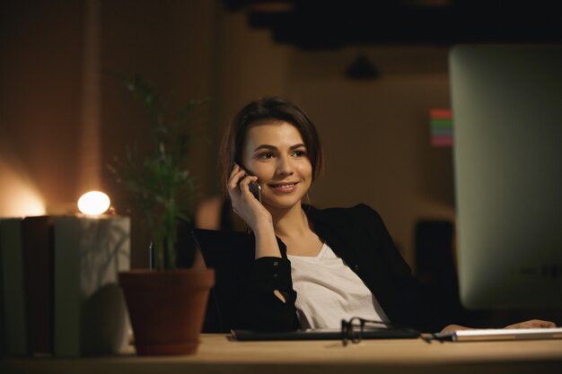 Progettista felice della giovane donna che parla dal telefono