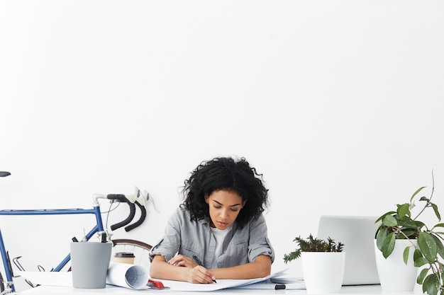 Progettista femminile giovane e laborioso concentrato che disegna il modello