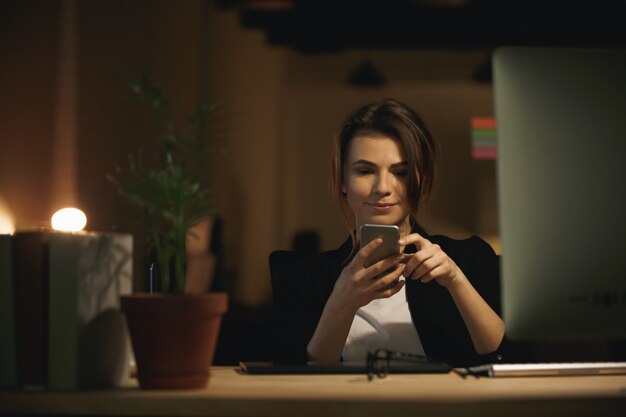 Progettista grazioso della giovane donna che si siede all'interno che chiacchiera dal telefono