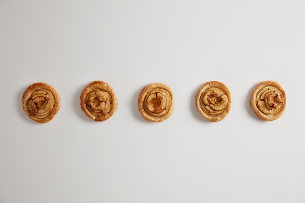 Pronto a mangiare. Dolci e gustosi turbinii cotti dal pasticcere professionista nel panificio. Sfondo bianco, vista dall'alto. . Colazione gustosa, pasticceria appetitosa