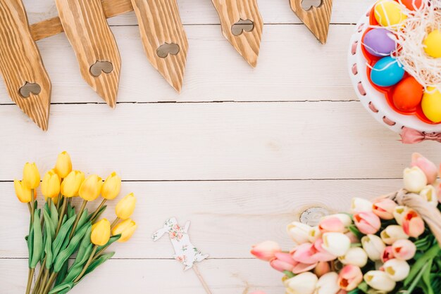 Prop di Pasqua; tulipani; uova di Pasqua; tulipani e recinzione sulla scrivania in legno