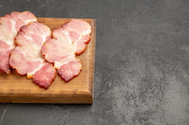 Prosciutto affettato di vista frontale sulla scrivania di legno e maiale crudo del pasto della carne della foto grigia