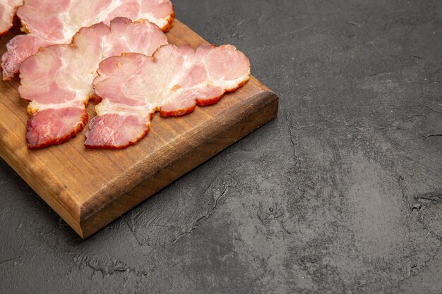 Prosciutto affettato di vista frontale sulla scrivania di legno e maiale crudo di farina di carne di colore grigio con foto