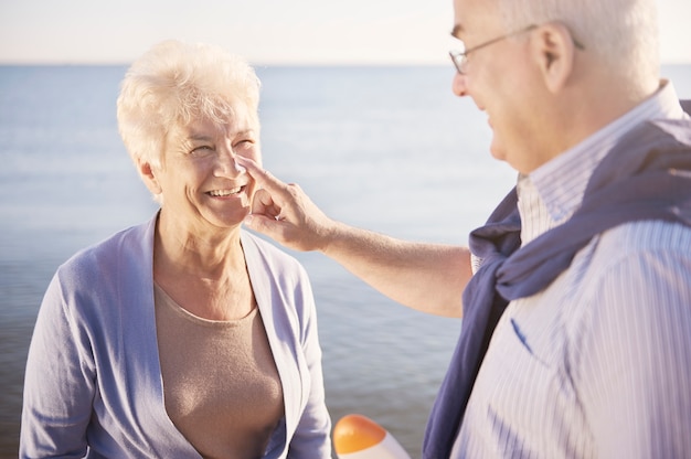 Protezione solare in spiaggia. Coppia senior in spiaggia, il pensionamento e il concetto di vacanze estive