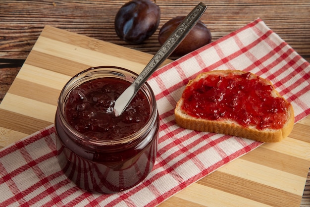 Prugne con un barattolo di confettura e un pane tostato.