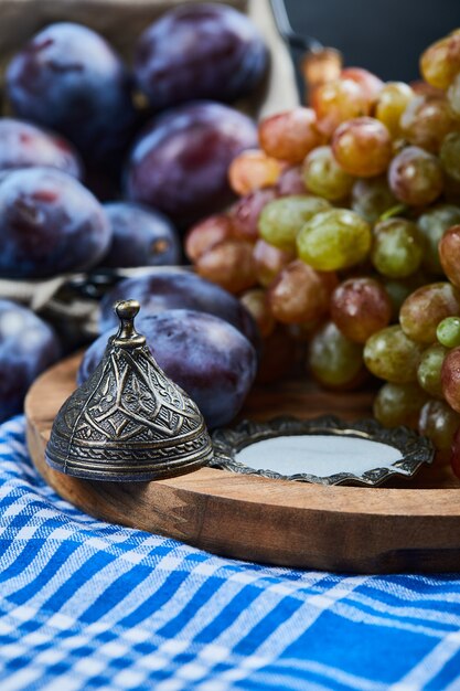 Prugne fresche e un grappolo d'uva su una tovaglia