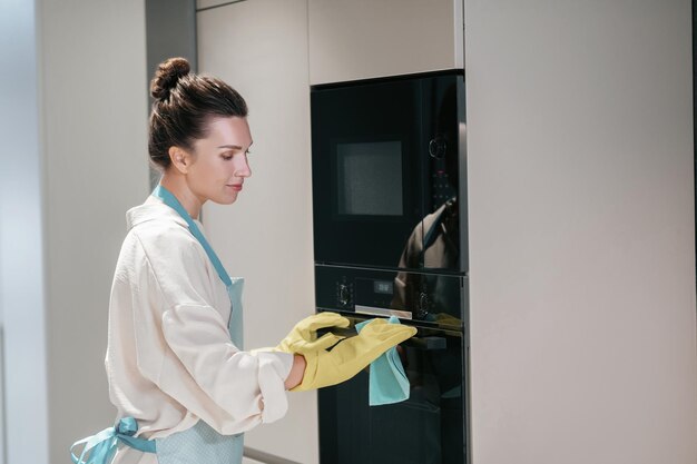 Pulizia. Giovane donna dai capelli scuri che pulisce in cucina