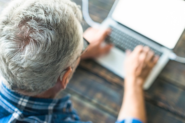 Punto di vista ambientale dell&#39;uomo senior che per mezzo del computer portatile