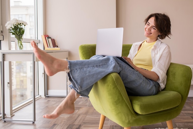 Punto di vista completo della donna attraente a casa che lavora al computer portatile