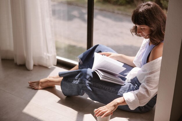 Punto di vista completo della donna che esamina il libro a casa